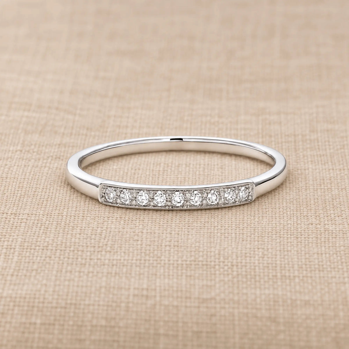 Balto aukso žiedas su deimantais, 0.05 ct, 0.75 g ant šilto smėlinio audinio – ADORO juvelyrika