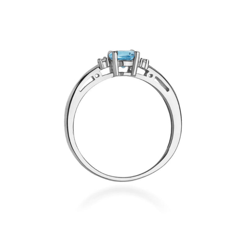 
                  
                    Balto aukso žiedas su 0.5 ct topazu ir briliantais – subtili elegancija ir moderni prabanga viename papuošale.

Žiedo centre puikuojasi 0.5 ct natūralus topazas – dažniausiai šviesiai mėlynos spalvos akmuo, simbolizuojantis aiškumą, vidinę ramybę ir harmoniją. Jo skaidrus, gaivus atspalvis puikiai dera su 585 arba 750 prabos balto aukso šaltu blizgesiu, suteikdamas žiedui modernų ir rafinuotą įvaizdį. Aplink topazą spindintys briliantai pabrėžia jo žavesį ir prideda papildomo švytėjimo.
                  
                