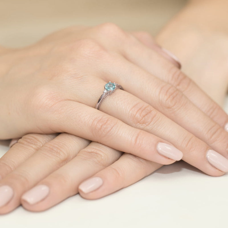 
                  
                    Balto aukso žiedas su 0.5 ct topazu ir briliantais – subtili elegancija ir moderni prabanga viename papuošale.

Žiedo centre puikuojasi 0.5 ct natūralus topazas – dažniausiai šviesiai mėlynos spalvos akmuo, simbolizuojantis aiškumą, vidinę ramybę ir harmoniją. Jo skaidrus, gaivus atspalvis puikiai dera su 585 arba 750 prabos balto aukso šaltu blizgesiu, suteikdamas žiedui modernų ir rafinuotą įvaizdį. Aplink topazą spindintys briliantai pabrėžia jo žavesį ir prideda papildomo švytėjimo.
                  
                