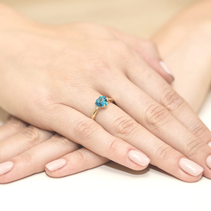 
                  
                    Geltono aukso žiedas su 1.7 ct topazu ir briliantais "Širdis" – išskirtinis, romantiškas ir elegantiškas papuošalas, atspindintis meilę, šilumą ir harmoniją.

Žiedo centre – 1.7 ct natūralus topazas, išformuotas į širdies formą, kurios šviesiai mėlynas atspalvis gražiai dera su geltono aukso šiltu spindesiu. Topazo gaivus ir ryškus blizgesys, kartu su briliantais, kurie puošia žiedą aplink širdies formą, suteikia šiam papuošalui prabangos, žavesio ir išskirtinumo.
                  
                