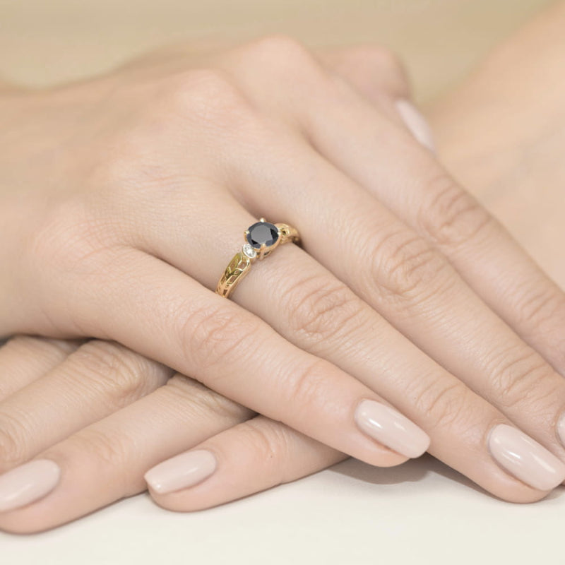 
                  
                    Žiedo centre spindi 0.5 ct juodasis deimantas, kuris suteikia šiam papuošalui drąsos ir modernumo. Jo tamsi, paslaptinga spalva puikiai dera su raudono aukso šiluma, sukuriant unikalų kontrastą. Aplink juodąjį deimantą išdėstyti briliantai prideda žvytėjimo ir elegancijos, suteikdami žiedui papildomo švytėjimo ir prabangos.
                  
                